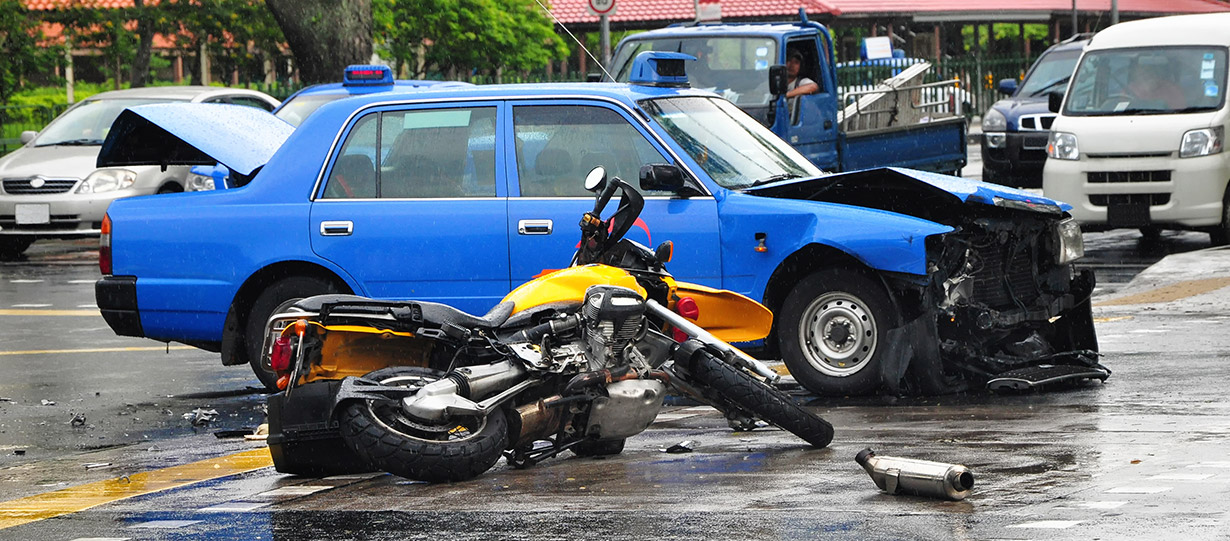 A car and a motorcycle are both wrecked in the middle of the road.