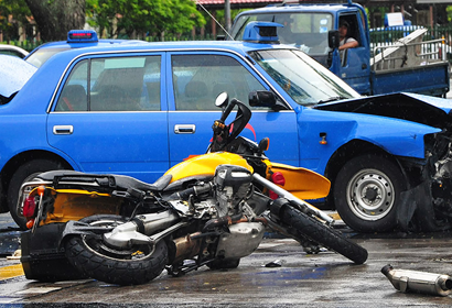 A car and a motorcycle are both wrecked in the middle of the road.
